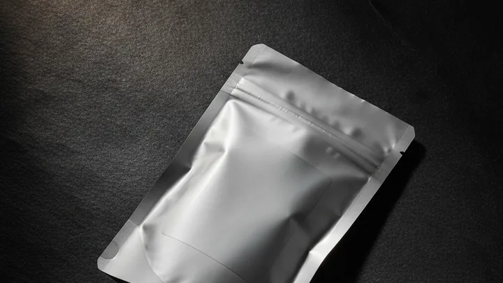 Imej ilustrasi dijana AI — sebuah pouch makanan bertutup rapat terletak di atas batu tulis gelap, dengan ruang label di hadapannya dibiarkan kosong sepenuhnya tanpa sebarang cetakan