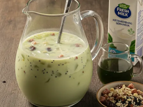 Jag kaca besar diisi susu dan sirap pandan hijau, dengan bahan rendaman katira, kembang semangkuk, kurma serta biji selasih dan badam cincang yang dikacau rata