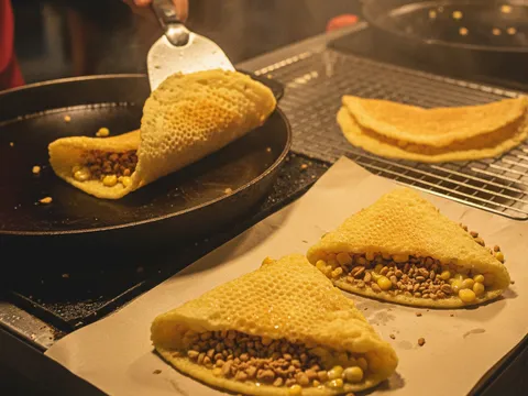 Apam balik dilipat separa bulan dan dipotong, inti kacang dan jagung krim terkeluar sedikit di tepi