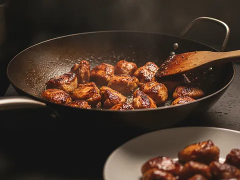 Ketulan ayam berperap digoreng kilas dalam kuali panas sehingga tepinya keperangan