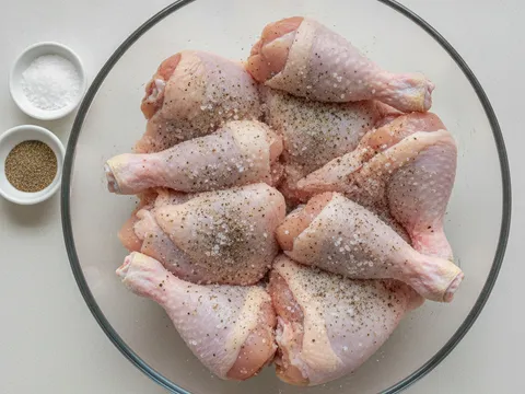Ketulan ayam digaul dengan garam dan serbuk lada hitam dalam mangkuk kaca sebelum diperap