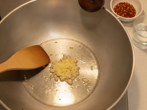 Bawang putih cincang ditumis dalam kuali sehingga wangi sebelum air dan kicap manis dituang