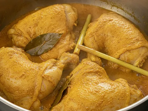 Ketul ayam diungkep dalam kuah rempah kuning pekat bersama serai dan daun salam dalam periuk
