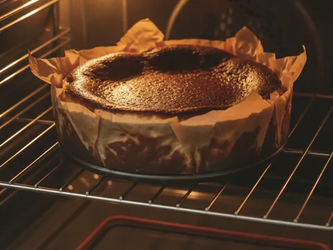 Burnt cheesecake dalam oven dengan permukaan atas gelap hangus dan tepi yang naik tinggi