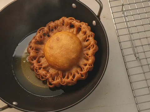 Cucur jawa yang sudah masak ditolak ke tepi kuali untuk menyejatkan lebihan minyak sebelum ditoskan