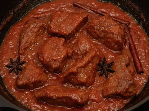 Hirisan daging empuk digaul dalam kuah merah pekat berkilat dengan minyak merah naik di tepi kuali