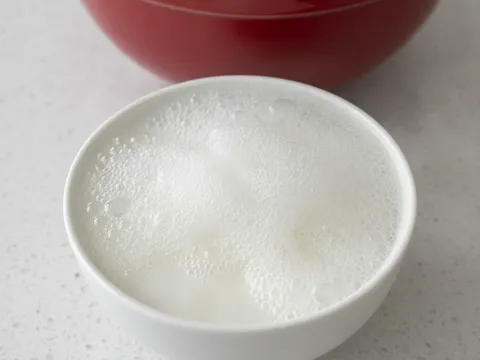 Soda bikarbonat bercampur cuka putih berbuih naik dalam mangkuk kecil putih, sedia dituang ke dalam adunan kek