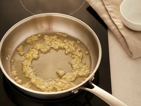 Bawang putih cincang digoreng keemasan dalam minyak di dalam kuali kecil