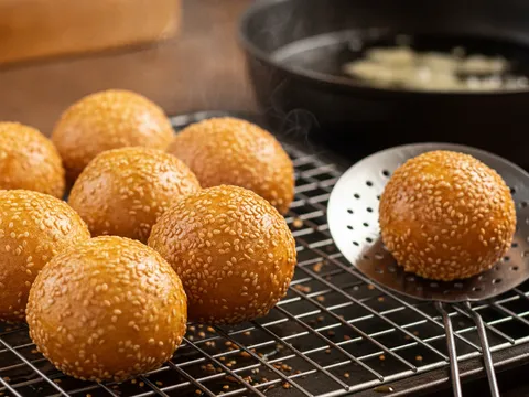 Kuih bom bijan keemasan diangkat dari minyak dan ditoskan di atas redai dawai