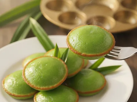 Kuih cara manis hijau diangkat dari acuan dengan garfu dan disusun berpasangan di atas pinggan