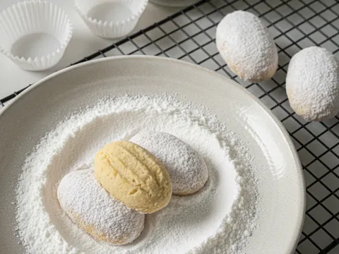 Kuih makmur sejuk digolek dalam pinggan gula aising sehingga bersalut putih tebal