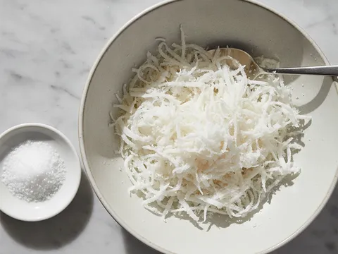 Kelapa parut putih digaul dengan tepung jagung dan garam halus dalam mangkuk menggunakan hujung jari