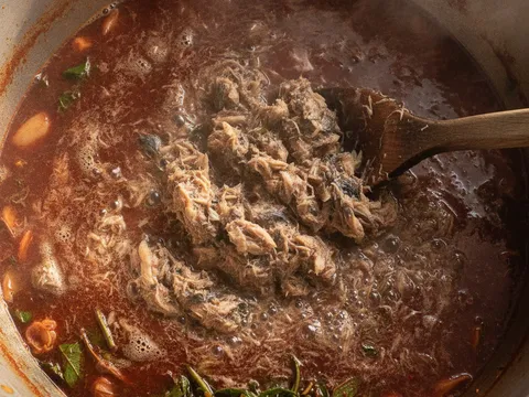 Isi ikan kembung carik dimasukkan ke dalam kuah asam laksa yang sedang mereneh, kuah pekat berserabut