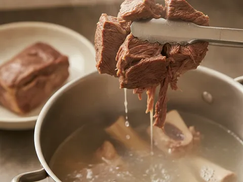 Ketulan daging lembu empuk diangkat dari periuk rebusan tulang dengan penyepit
