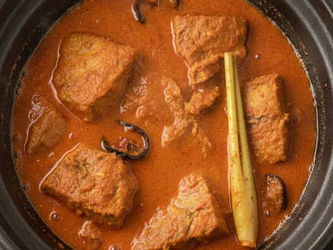 Gulai ikan tongkol pekat berwarna jingga dengan minyak naik ke permukaan, ketul ikan kekal elok