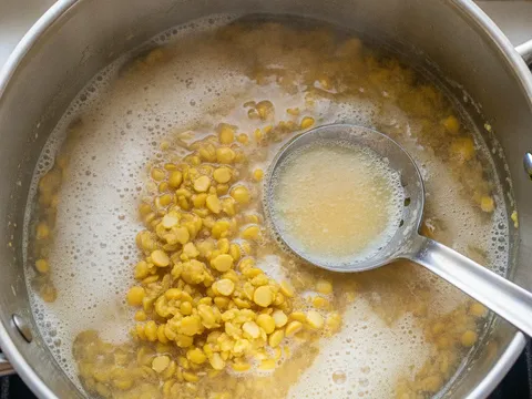 Kacang dhal kuning direbus dalam periuk sehingga lembut dengan buih dibuang dari permukaan