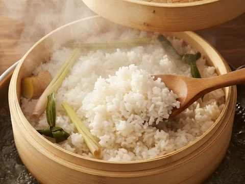 Nasi uduk dikukus dalam kukusan beruap dan digaul dengan senduk kayu di pertengahan masa mengukus