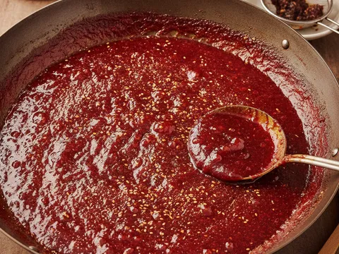 Sira sambal merah pekat berkilat berbuih halus dalam kuali dengan bijan ditabur