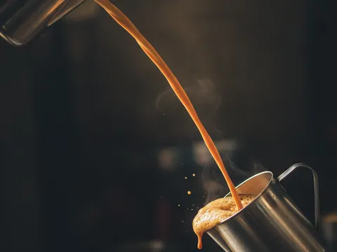 Aliran panjang teh tarik dituang dari jag tinggi ke jag di bawah, buih mula terbentuk di permukaan